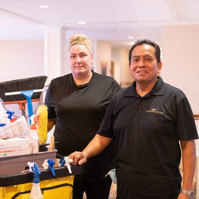 Staff members with cleaning supplies in a hallway