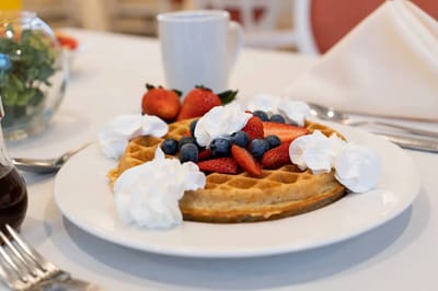 Plate of waffles topped with fruit and whipped cream