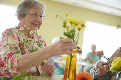 Residents arranging flowers in a bright communal area