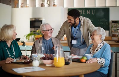 Residents enjoying breakfast with staff in a dining area
