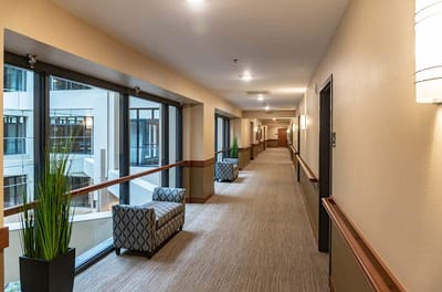 Well-lit hallway with seating in a senior living facility