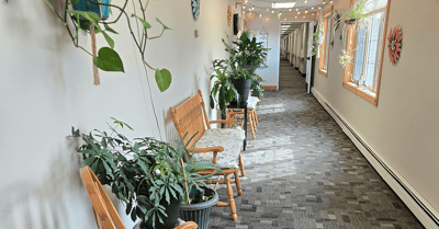 A hallway with plants and benches in a senior living facility