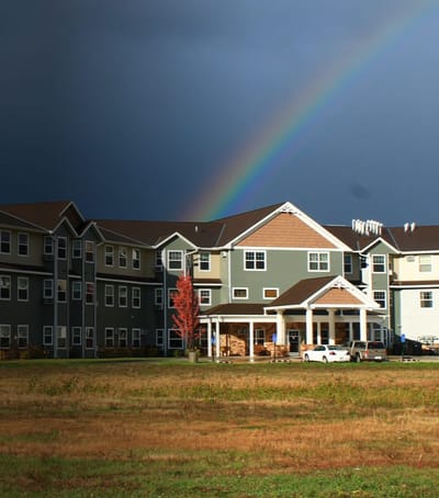 Exterior view of a senior living facility with a rainbow