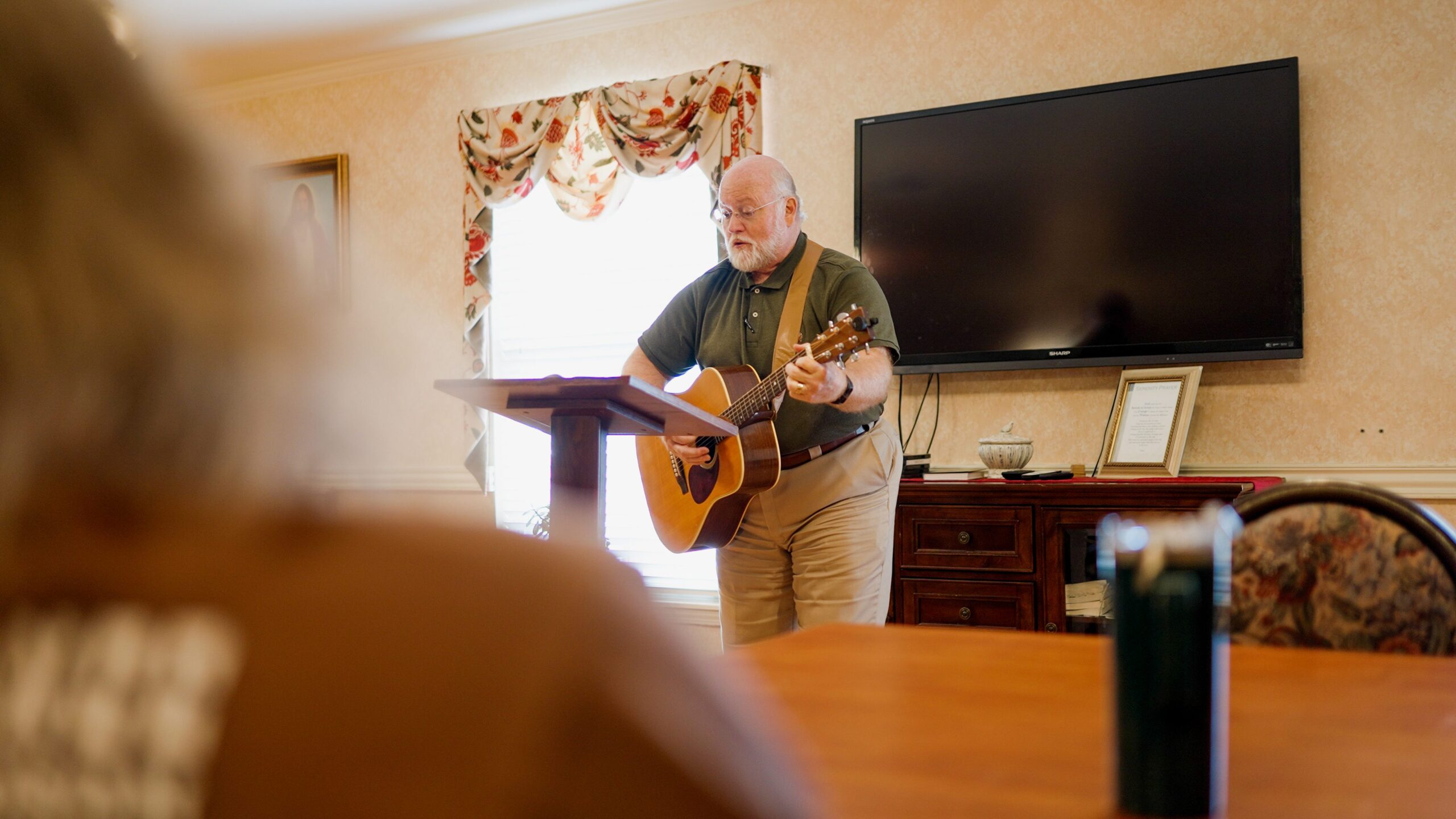Man playing guitar for residents in an activity room