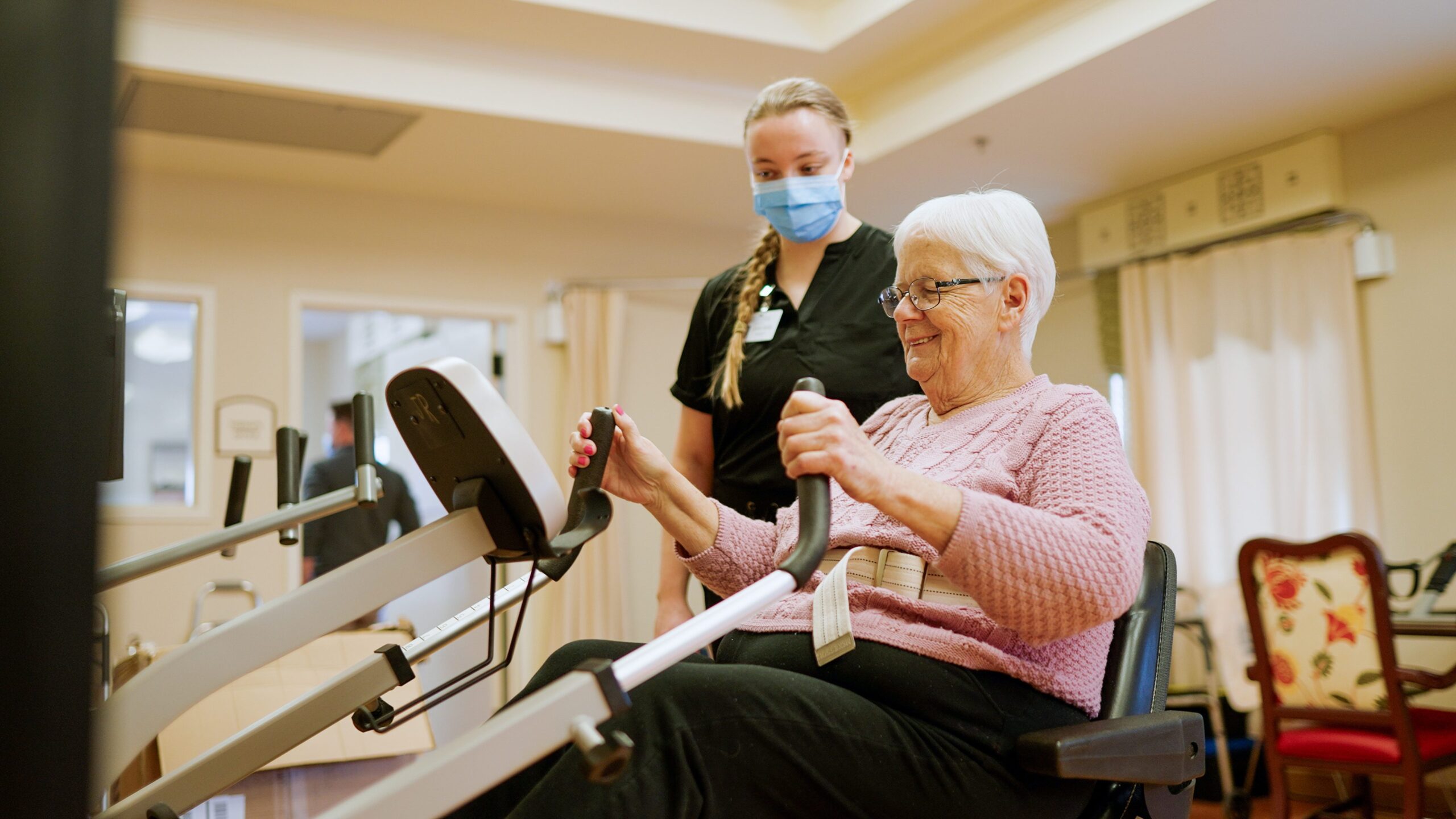 Resident engaging in exercise with staff support
