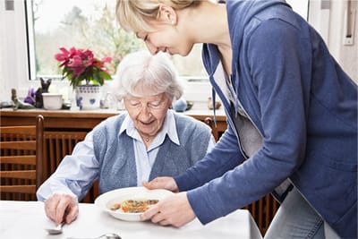 Staff serving a meal to a resident in dining area