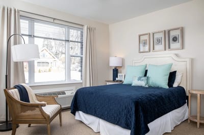 A well-decorated private resident room with a bed and chair