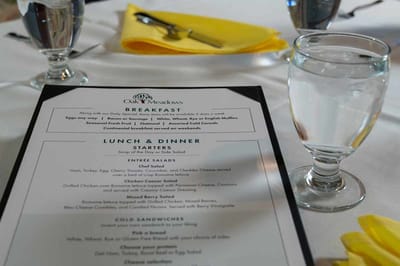 Menu on a table with water glass, featuring meal options