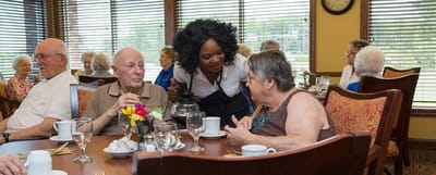 Residents enjoying a meal in the dining room with staff assistance