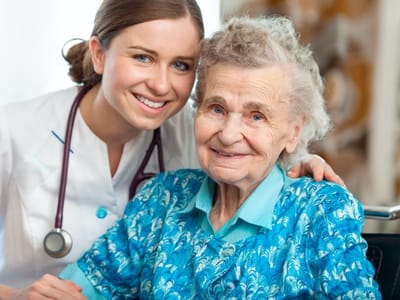 A nurse and resident smiling together in a care setting
