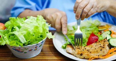Resident enjoying a meal with a salad and grilled fish