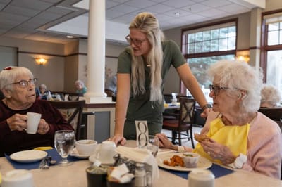 Residents enjoying a meal with a caregiver in the dining area