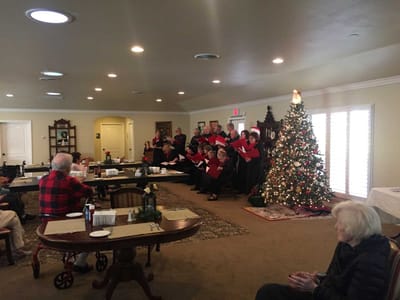 Residents enjoy a holiday choir performance indoors.