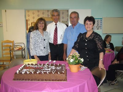 Celebration with residents and staff around a cake.