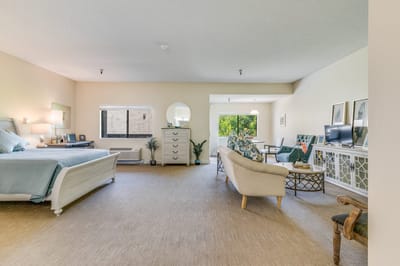 Spacious resident room with seating and light decor.