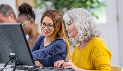 Residents engaging in computer activities with staff assistance.