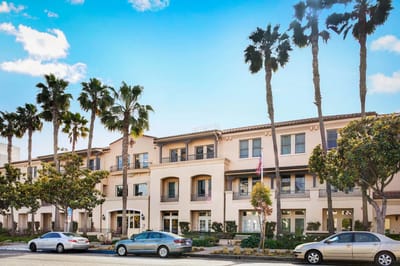 Exterior view of assisted living facility with palm trees.