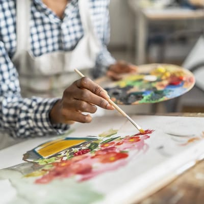 Person painting flowers on canvas