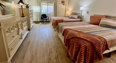Cozy resident room with two beds and light decor.