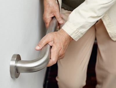 Elderly person's hand gripping a handrail