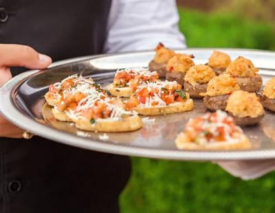 A server holding a tray of gourmet appetizers.