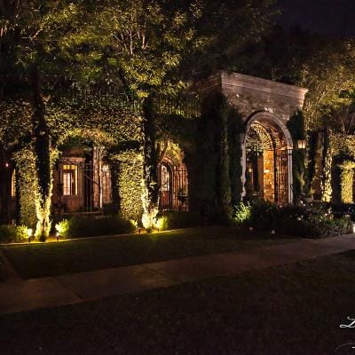 Illuminated entryway with lush greenery at night.