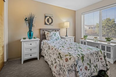 Cozy private bedroom with floral bedding and lamp.