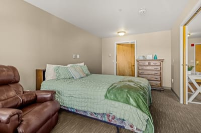 Cozy resident room with a bed and chair.