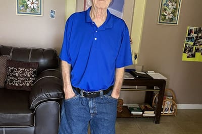 Senior man in a blue shirt standing indoors