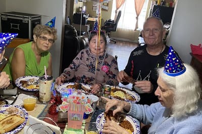 Residents celebrating with food and party hats.