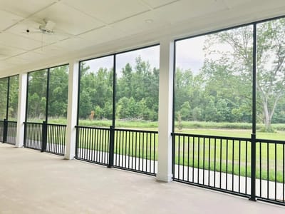 Covered area with large windows overlooking greenery.