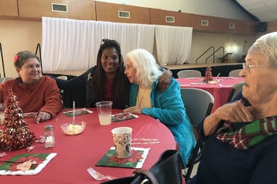 Residents enjoying a meal and conversation at a dining table.