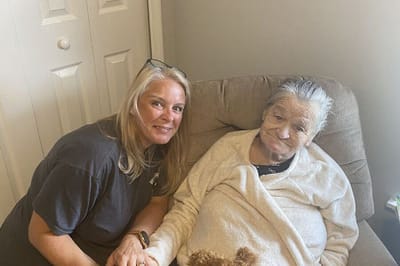 Staff member with an elderly resident in a cozy setting.