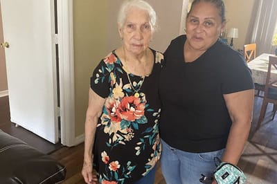 Resident and staff member posing together indoors.