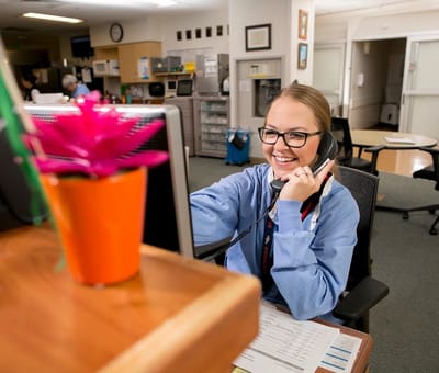 Staff member at reception desk talking on the phone.