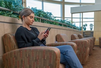 Young woman sitting in a common area using a phone.