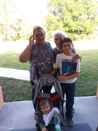 Two women and two children outside smiling together.