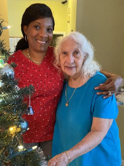 Caregiver and senior resident by a decorated tree