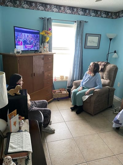 Two women in a living room setting watching TV.