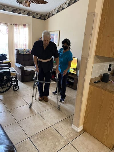 Staff assisting a resident with mobility in an interior space.
