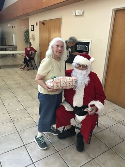 Elderly woman with Santa Claus at a holiday event.