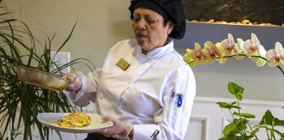 A chef serving an omelette in the kitchen.