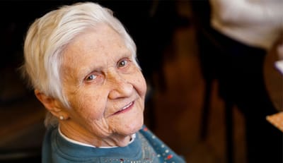 Smiling elderly woman in a facility setting.
