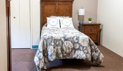 Cozy bedroom with floral bedding and bedside table.