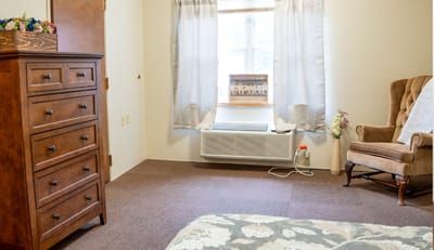 Cozy resident room with a dresser and armchair