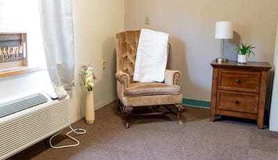 Cozy reading corner with armchair and lamp.