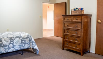 A spacious private room with a dresser and bed.