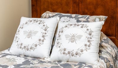 Decorative pillows on a bed with floral bedding.