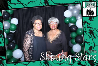 Two women posing at an event backdrop.