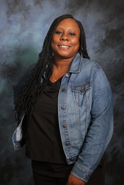 Smiling staff member in a denim jacket.